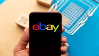 Ekranda eBay logolu bir akıllı telefon tutan kişiyi gösteren resim