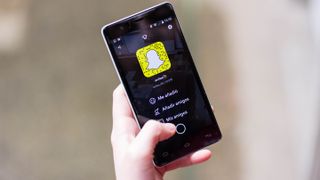 Telefonunda Snapchat menüsüne bakan bir kişi