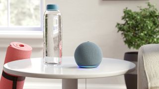 Bir su şişesi ve bir yoga matının yanında bir masada oturan Echo Dot.