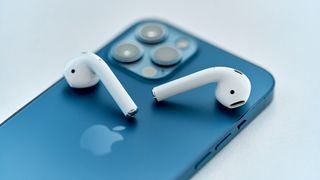 Bazı AirPod'ların üstte durduğu bir iPhone'un arkası