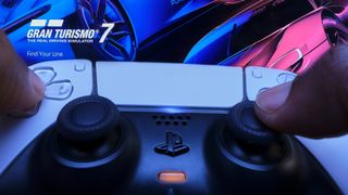 PS5 DualSense denetleyicisi, Gran Turismo 7 kontrol panelini gösteren bir TV'yi işaret etti