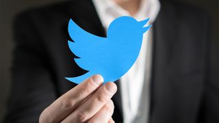 Twitter logosu tutan takım elbiseli bir adam