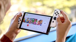 Nintendo Switch OLED, JoyCon'lardan biri kaydırılarak iki el arasında tutuldu