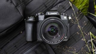 Bir sırt çantasının üzerinde duran Panasonic G80 fotoğraf makinesi