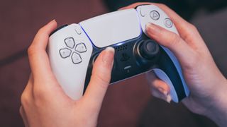 PS5 DualSense kontrol cihazını tutan kadın