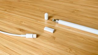 Bir Lightning kablosu, kapağı çıkarılmış birinci nesil Apple Pencil ve Apple Pencil şarj adaptörü