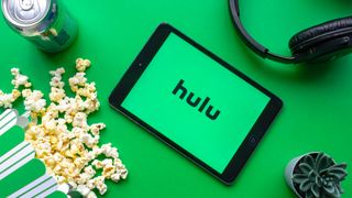 Patlamış mısır, soda, kulaklık ve kaktüsle çevrelenmiş Hulu logosuna sahip bir tablet