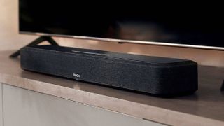 Denon Home Sound Bar 550, boş, siyah ekranlı bir TV'nin altında