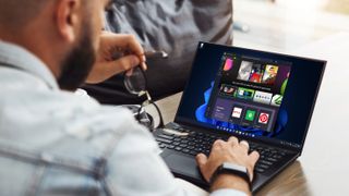 Windows 11'in Microsoft Store uygulaması açıkken dizüstü bilgisayar kullanan bir adamın arkadan görünümü