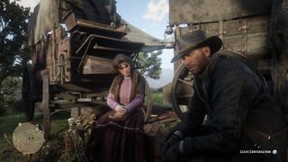 Red Dead Redemption 2 - İki kişi bir kamp alanında vagonların önünde oturuyor