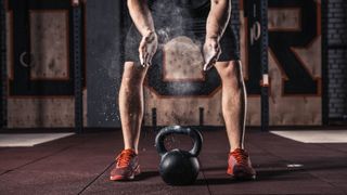 kettlebell sallanmadan önce ellerine tebeşir koyan bir adamın fotoğrafı