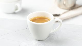 Espresso yapmayı temsil eden taş bir tezgah üzerinde bir fincan espresso