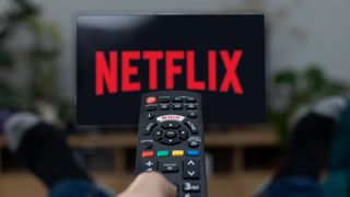 Bir uzaktan kumandanın işaret edildiği bir TV ekranında Netflix logosu