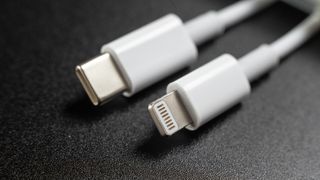 Siyah arka planda telefon için USB-C ve Lightning şarj kabloları