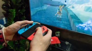 TV'de Breath of the Wild oynamak için Joy-Con denetleyicilerini kullanan bir Nintendo Switch oyuncusu