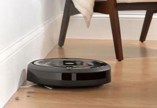 irobot roomba e5 arka planda bir sandalye ile sert ahşap döşemeyi temizliyor