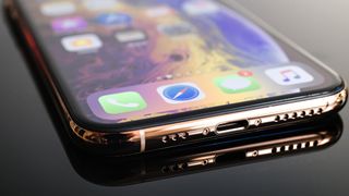 Hoparlörlerin iPhone hoparlörlerinin nasıl temizleneceğini göstermeye hazır olduğunu gösteren bir iPhone'un alt yarısı